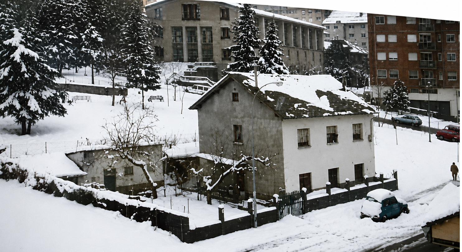 La casa ya revocada y enfoscada, cubierta de nieve, rodeada de edificios modernos